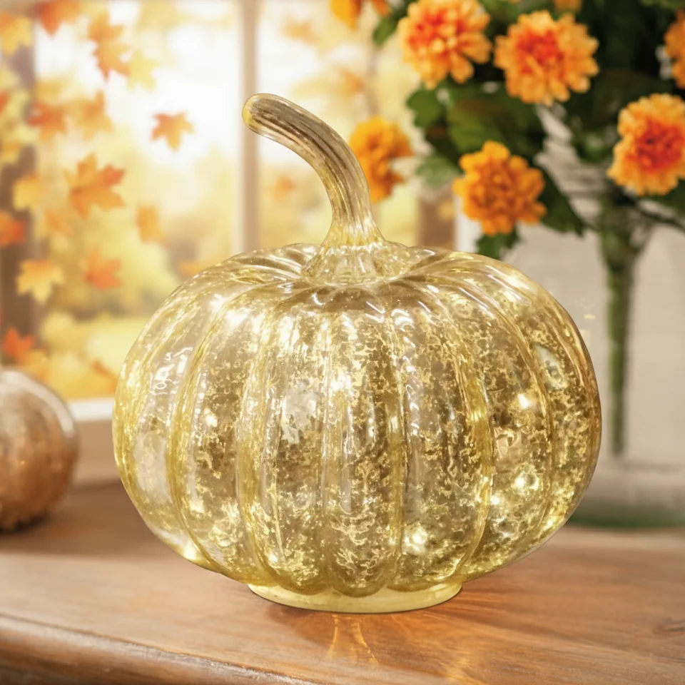 Gold-tone glass pumpkin with a curved stem and a textured decorative surface.