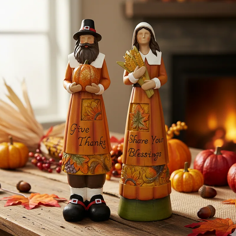 Pair of harvest figures in traditional-style clothing, each holding a pumpkin.